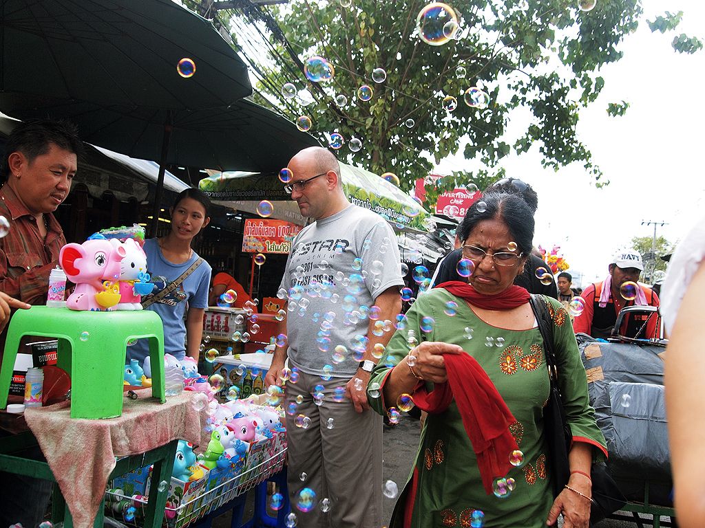 A passer by burst bubbles in a busy Thai Market